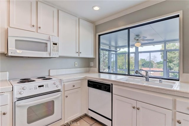 kitchen featuring light tile patterned floors, white appliances, a sink, and white cabinets