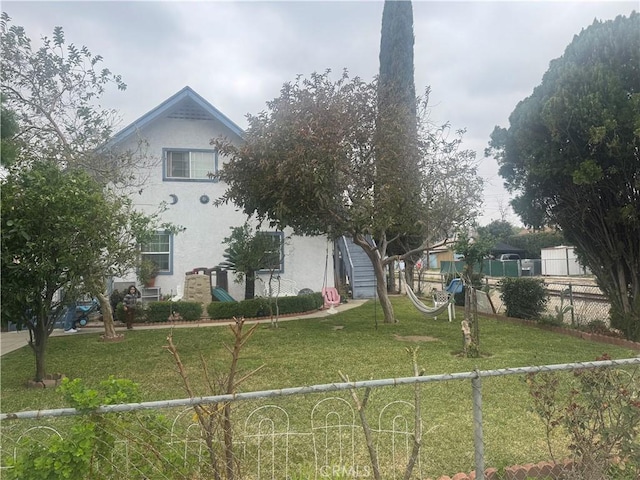 view of front facade with stucco siding, fence private yard, and a front lawn