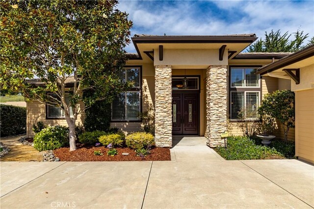 doorway to property with stone siding and stucco siding