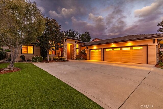 prairie-style home featuring driveway, an attached garage, and a yard