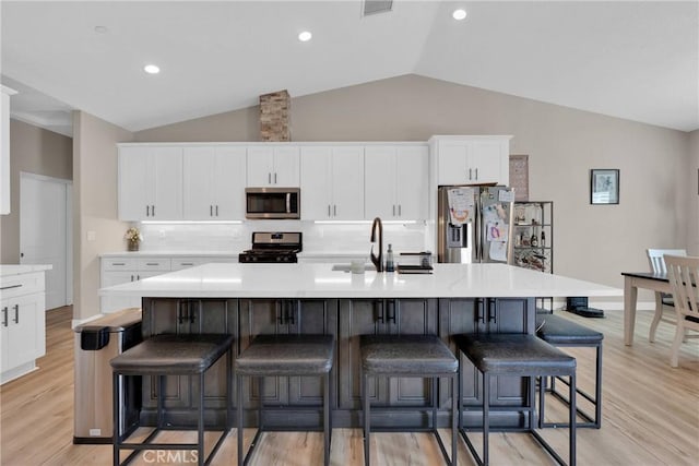 kitchen featuring lofted ceiling, white cabinetry, stainless steel appliances, and light countertops