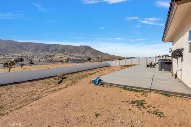 view of yard with a patio area, a fenced backyard, and a mountain view