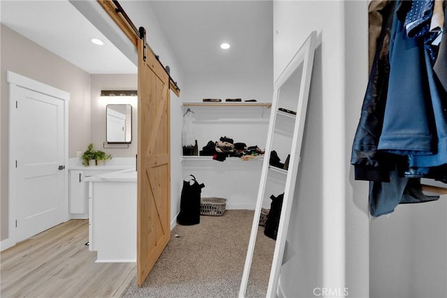 spacious closet with light wood finished floors and a barn door