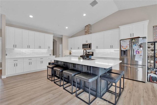 kitchen featuring an island with sink, visible vents, appliances with stainless steel finishes, and light countertops