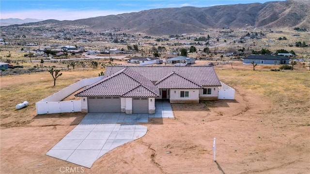 view of front of house featuring a mountain view, a garage, a tile roof, fence, and concrete driveway