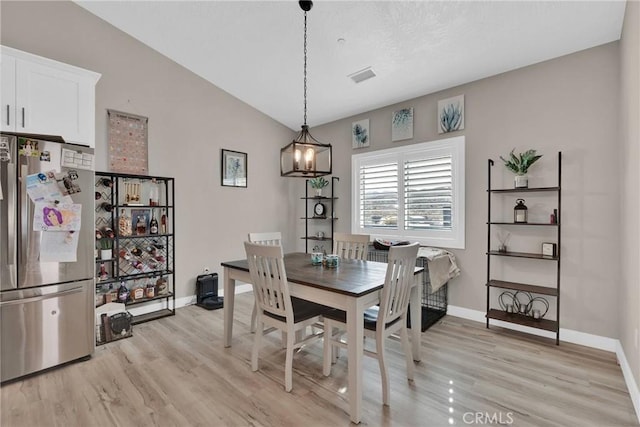 dining room with light wood-style floors, visible vents, baseboards, and an inviting chandelier