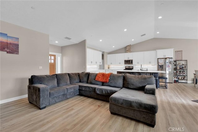 living area with light wood-style floors, recessed lighting, vaulted ceiling, and baseboards