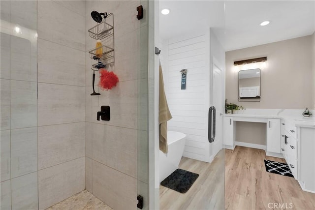 full bath featuring a freestanding tub, tiled shower, vanity, and wood finished floors