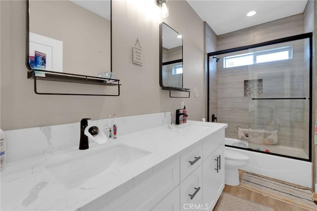 full bath featuring shower / bath combination with glass door, a sink, toilet, and wood finished floors