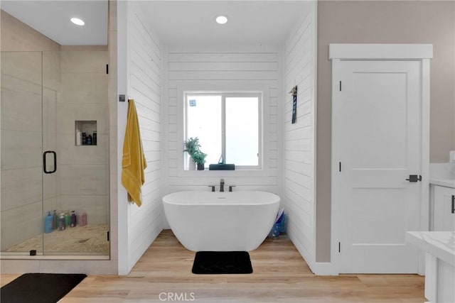 full bath featuring recessed lighting, a soaking tub, a shower stall, and wood finished floors