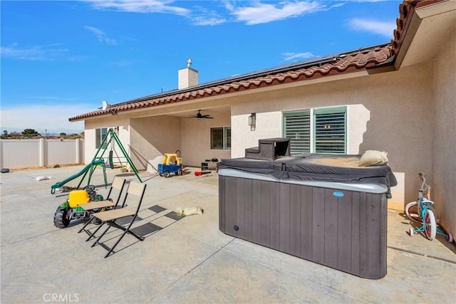 view of patio / terrace featuring a hot tub, fence, and ceiling fan