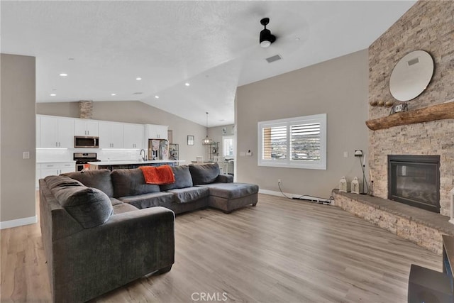 living area with lofted ceiling, light wood-style floors, a fireplace, and baseboards