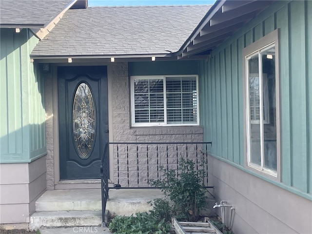 view of exterior entry featuring a shingled roof and board and batten siding