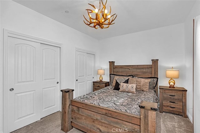 bedroom featuring carpet, an inviting chandelier, and two closets