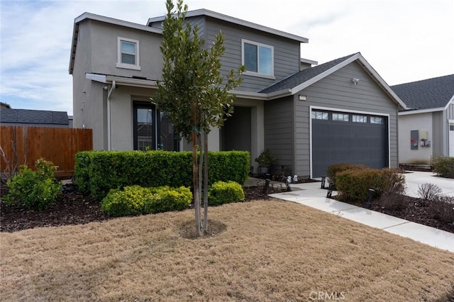 traditional home featuring a garage, driveway, and fence