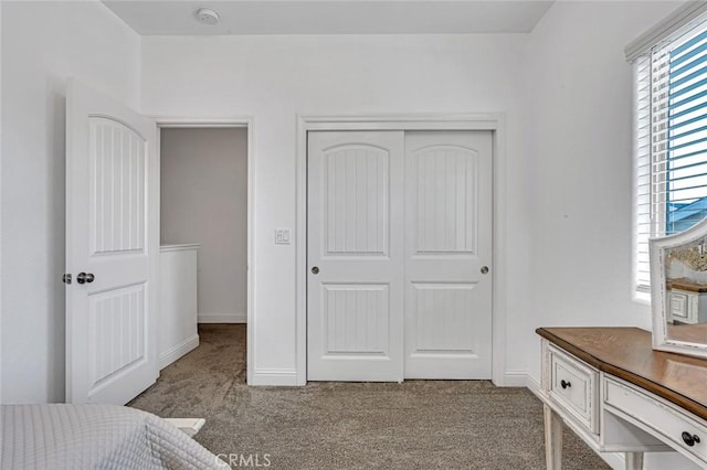 carpeted bedroom with a closet and baseboards