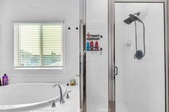 bathroom featuring a shower stall and a bath