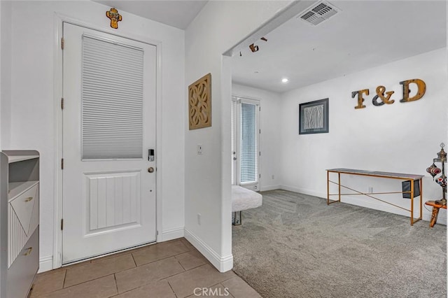 carpeted foyer entrance featuring tile patterned flooring, visible vents, baseboards, and recessed lighting