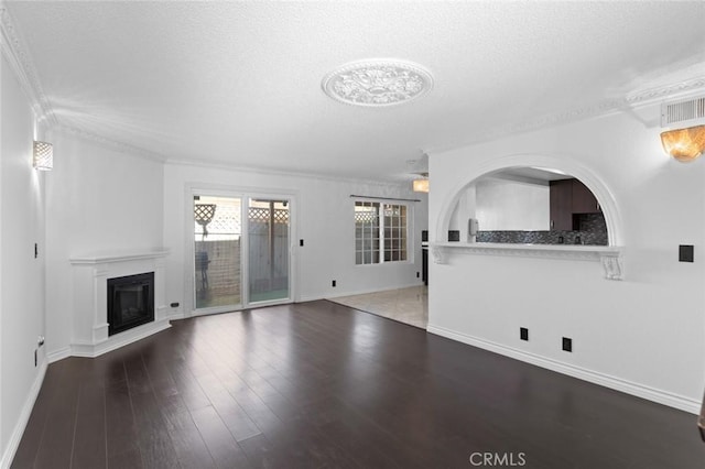 unfurnished living room with baseboards, visible vents, a glass covered fireplace, wood finished floors, and a textured ceiling