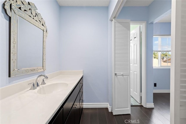 bathroom with wood finished floors, vanity, and baseboards