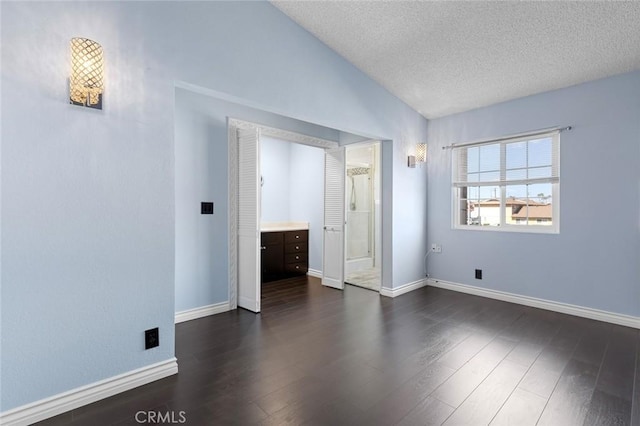 unfurnished bedroom with lofted ceiling, baseboards, dark wood finished floors, and a textured ceiling