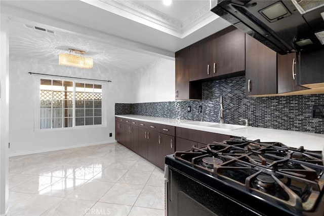 kitchen featuring tasteful backsplash, light countertops, ornamental molding, gas stove, and a sink