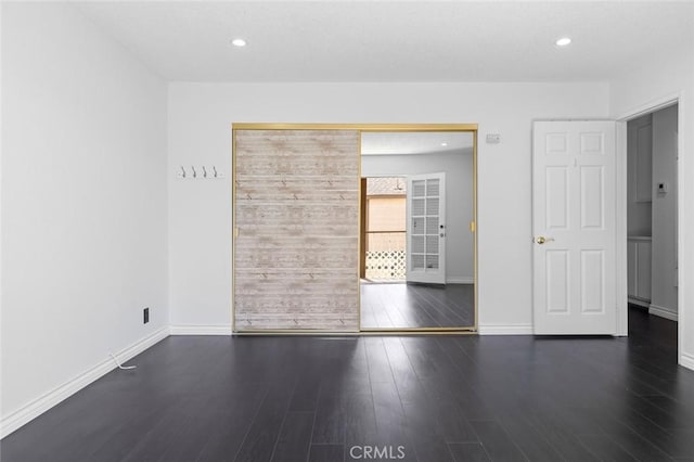 spare room featuring recessed lighting, wood finished floors, and baseboards