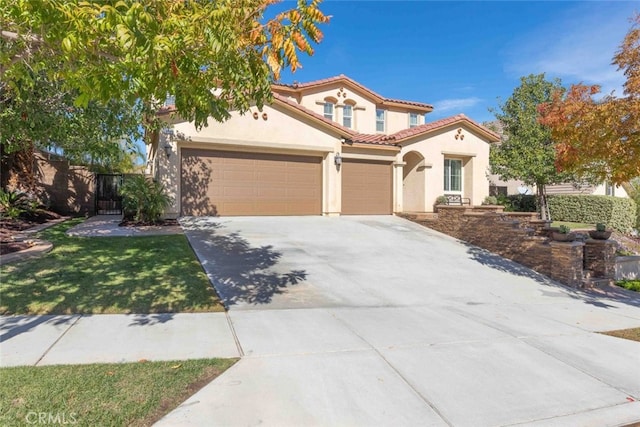 mediterranean / spanish-style home featuring fence, an attached garage, stucco siding, concrete driveway, and a tile roof