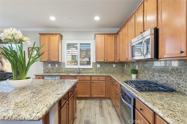 25499 Foxglove Ln, Corona, CA 92883 - kitchen featuring light stone counters, crown molding, a sink, light wood-style floors, and appliances with stainless steel finishes