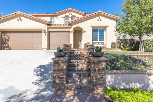 mediterranean / spanish-style home featuring stucco siding, concrete driveway, an attached garage, and a tiled roof