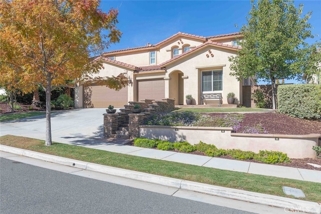 mediterranean / spanish home with a tiled roof, stucco siding, driveway, and a garage