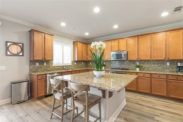 25499 Foxglove Ln, Corona, CA 92883 - kitchen with stainless steel appliances, light wood-style flooring, a kitchen island, and brown cabinetry