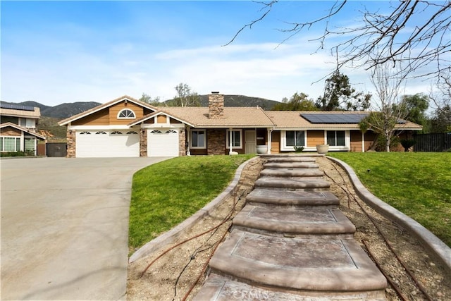 single story home with an attached garage, solar panels, concrete driveway, a front lawn, and a chimney