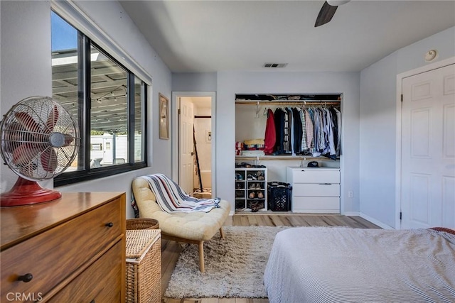 bedroom with ensuite bathroom, wood finished floors, visible vents, a ceiling fan, and a closet