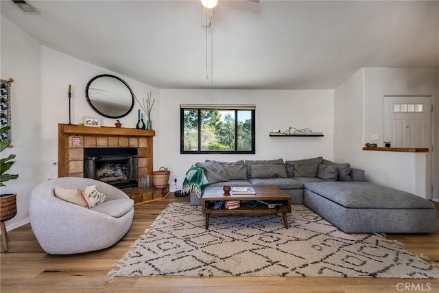 living room featuring visible vents, wood finished floors, and a tile fireplace