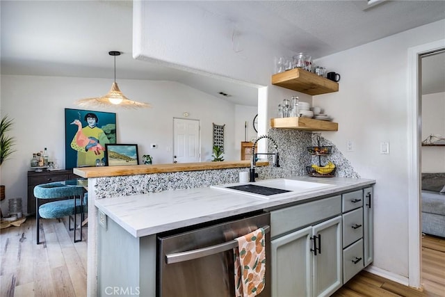 kitchen with gray cabinets, backsplash, light wood-style floors, a sink, and dishwasher