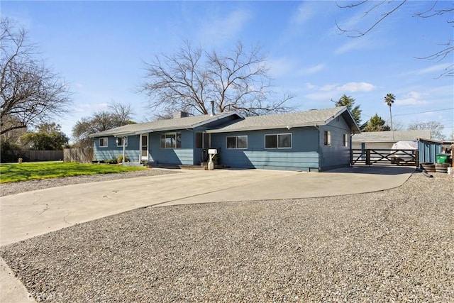 ranch-style home featuring concrete driveway and fence