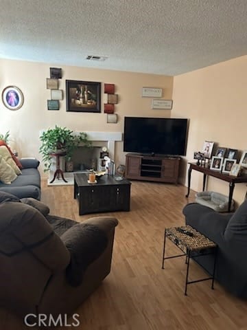 living area featuring visible vents, a textured ceiling, and wood finished floors