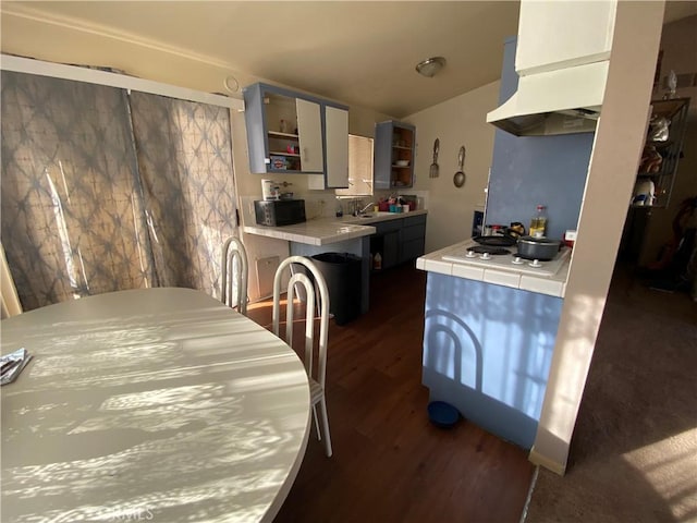 kitchen with dark wood-style flooring, a sink, tile counters, open shelves, and white electric stovetop