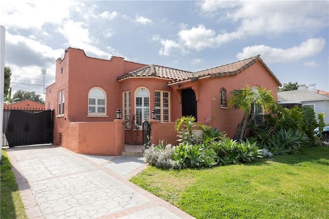 mediterranean / spanish house with a gate, a front lawn, and stucco siding