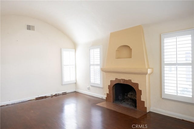 unfurnished living room with a fireplace, lofted ceiling, visible vents, wood finished floors, and baseboards