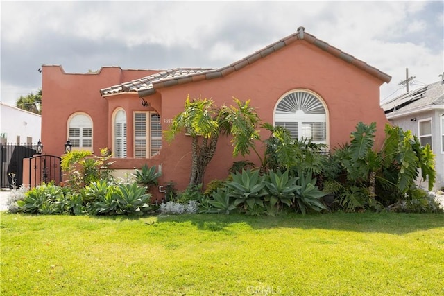 view of home's exterior with a tiled roof, a lawn, fence, and stucco siding