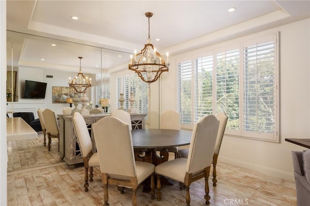 dining space featuring a chandelier, light wood-style flooring, recessed lighting, baseboards, and a tray ceiling