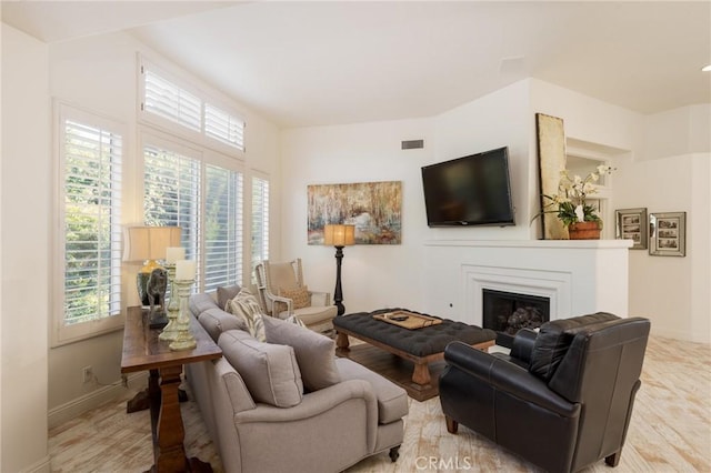 living room featuring plenty of natural light, a fireplace, and baseboards