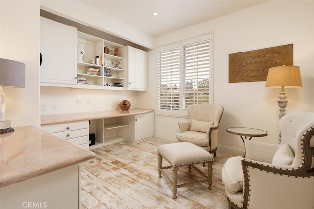 office space featuring light wood finished floors, built in desk, recessed lighting, and baseboards