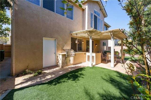 rear view of house featuring exterior kitchen, a yard, a patio area, a pergola, and stucco siding