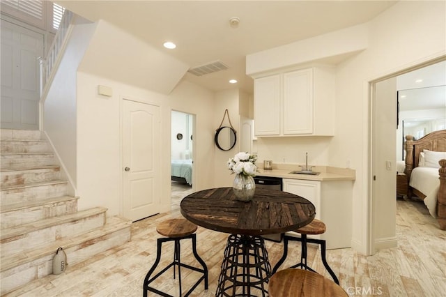 kitchen with visible vents, light countertops, white cabinetry, a sink, and recessed lighting