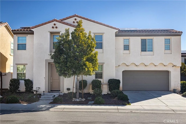 view of front of house with an attached garage, a tile roof, concrete driveway, and stucco siding