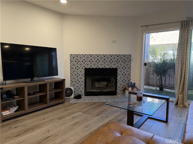 living room with a tiled fireplace and wood finished floors