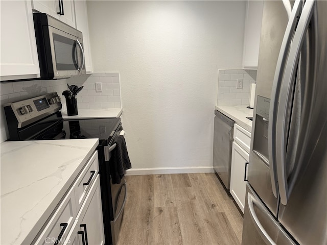 kitchen with light stone counters, decorative backsplash, appliances with stainless steel finishes, white cabinets, and light wood-type flooring